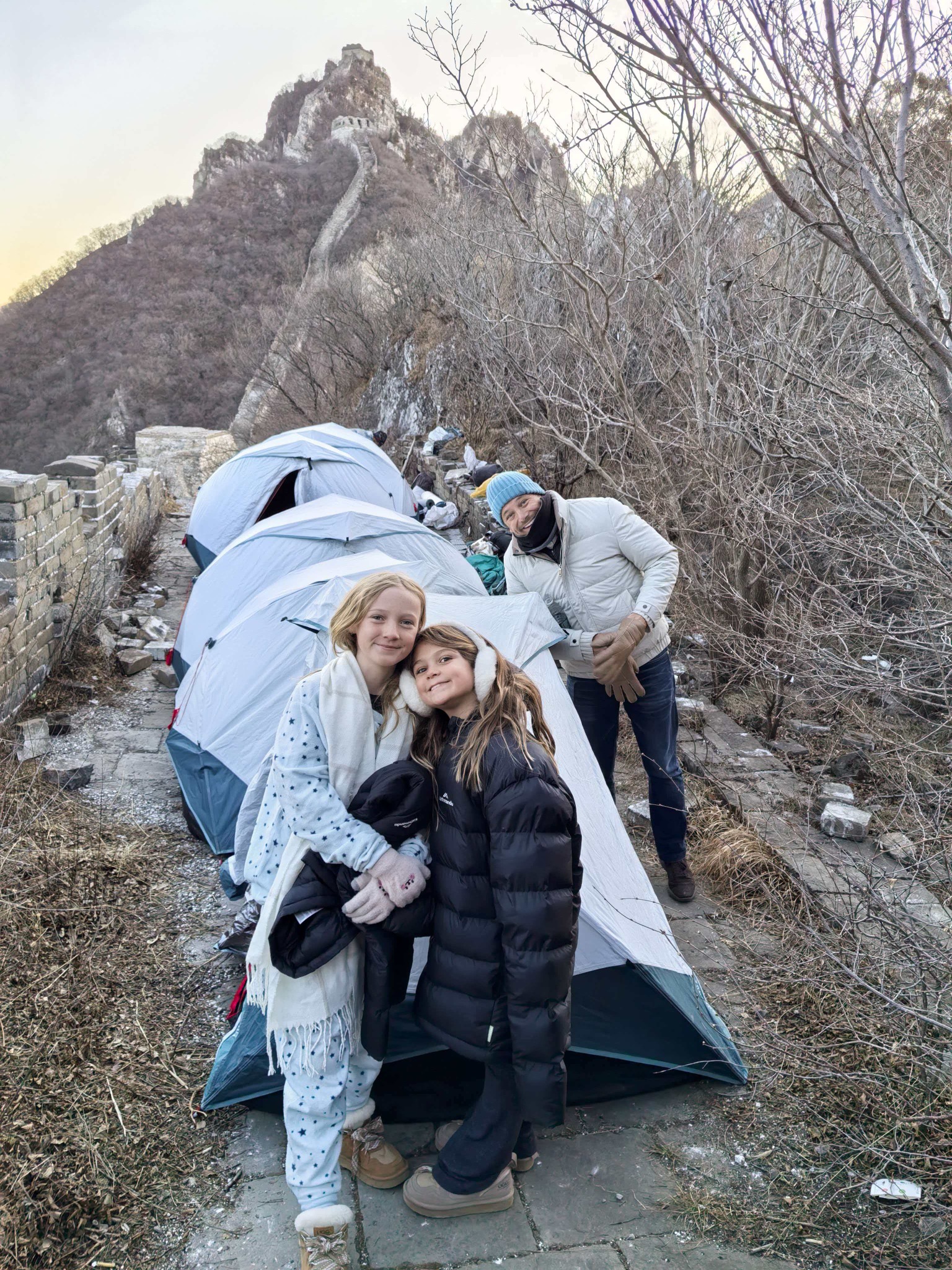 Guests beside tents on the Great Wall beneath a mountain watchtower